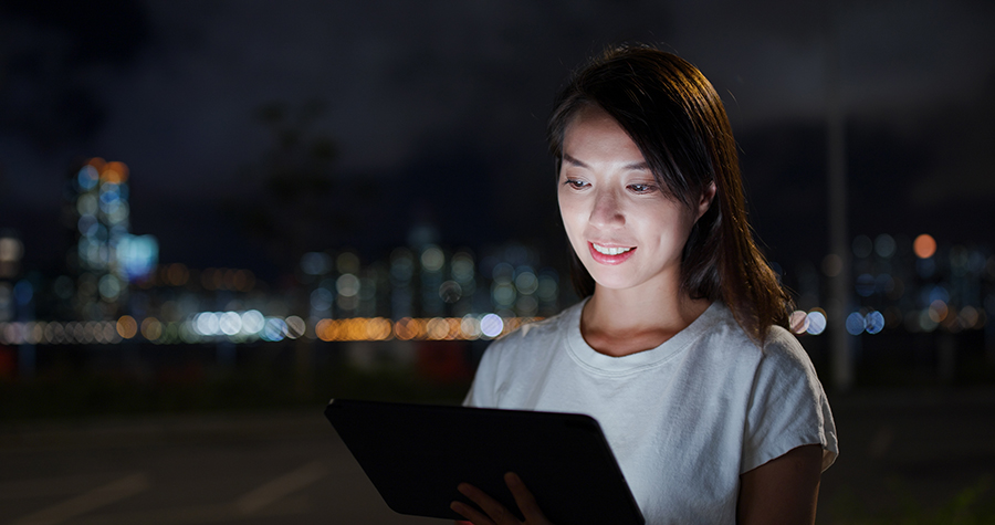 woman-read-on-tablet-computer-at-street-in-evening-HZ28NES